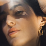 A close-up of a model wearing the Lucent Glow Starburst Linear Drop Earrings, showcasing the unique sun-inspired design, ideal for spiritual yoga practices and serving as a talisman for protection and positive energy.