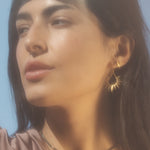 Close-up of the Lucent Glow Starburst Linear Drop Earrings worn by a model, capturing the essence of spiritual jewelry. The sunburst design evokes a sense of guidance and creativity, making these earrings a perfect talisman for meditation and meaningful practices in yoga.