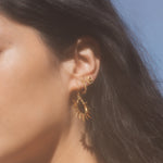 Side view of a model wearing the Lucent Glow Starburst Linear Drop Earrings combined with other ear jewelry, representing a harmonious blend of styles that reflect spirituality and personal manifestation through fashion.