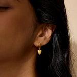 Close-up of the Loving Heart Huggie Earrings worn by a model, showcasing their elegant heart shape and sparkling white topaz, a perfect talisman for protection and an uplifting piece in spiritual jewelry for sun and moon manifestations.