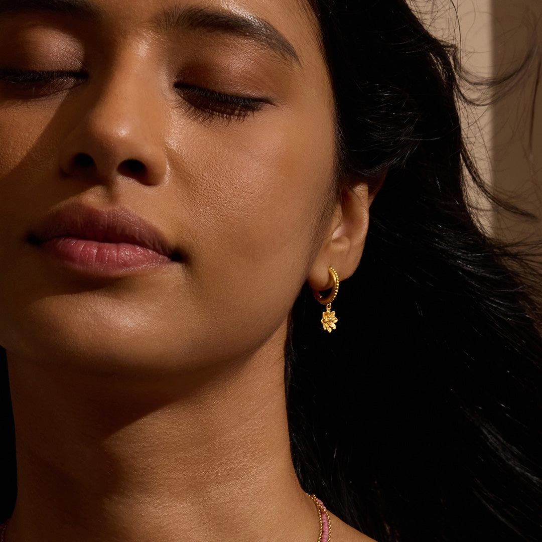 Model showcasing New Chapter Lotus Huggie Earrings, highlighting the elegant design symbolizing renewal and transformation, perfect for yoga enthusiasts and those seeking spiritual meaning and protection.