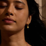 Model showcasing New Chapter Lotus Huggie Earrings, highlighting the elegant design symbolizing renewal and transformation, perfect for yoga enthusiasts and those seeking spiritual meaning and protection.