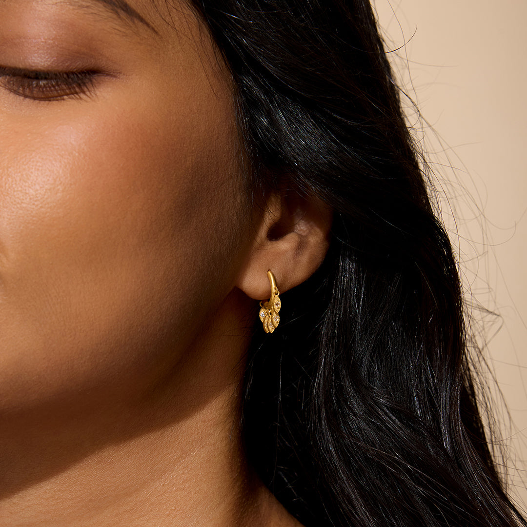 A woman wearing Scatter Light Huggie Earrings, showcasing the elegant design which symbolizes spiritual jewelry for meditation and manifestation. The earrings feature white topaz, connecting with meanings of protection and blessings related to the sun and moon, making them perfect for yoga and personal growth.