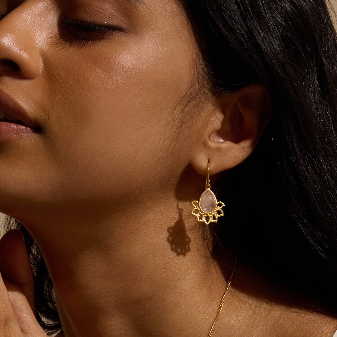 Close-up of a model wearing the Awakened by Love Rose Quartz Lotus Petal Earrings, emphasizing the delicate lotus petals and pear-shaped rose quartz. This spiritual jewelry piece is perfect for those seeking meaning in their accessories, serving as a powerful talisman during meditation and yoga, and symbolizing love, protection, and personal transformation.