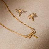 Pair of gold dragonfly earrings with white topaz stones and matching pendant necklace on gold chain.