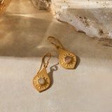 Pair of gold teardrop earrings with sun motif and opal stone centers on wire hooks.
