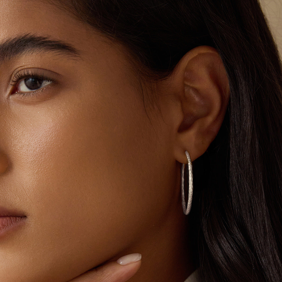 Close-up of a model wearing Textured Sterling Silver Large Hoop Earrings, showcasing their elegant design and versatility. This spiritual jewelry piece adds a meaningful touch to your look, perfect for meditation practices and embodying the essence of talismans. Embrace the connection to zodiac energies and protection while manifesting positivity through your style.