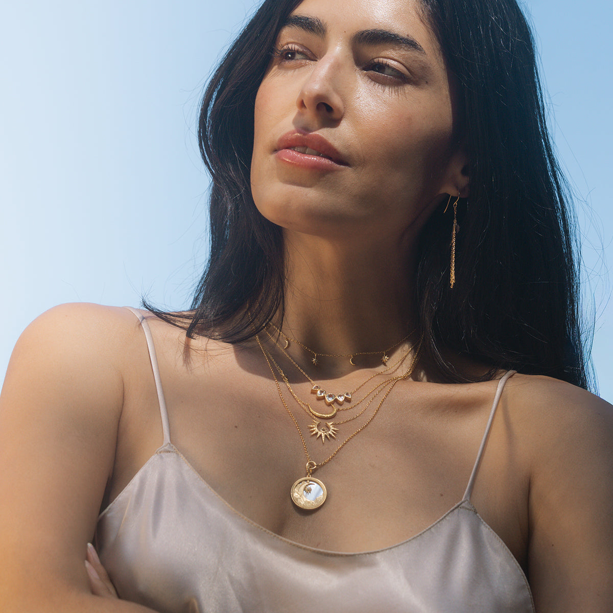 Waking Dreams Mother of Pearl Celestial Necklace worn by a model against a bright sky, symbolizing guidance and goddess energy. This piece of spiritual jewelry serves as a talisman for yoga enthusiasts seeking meaning and manifestation in their practice.