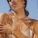 The Dreams Celestial Sun and Moon Lariat Necklace is worn by a woman, layered amidst other spiritual jewelry. The design reflects the elegance of the sun and moon, providing a beautiful symbol for meditation and manifestation, perfect for yoga and spiritual practices.