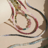 Close-up of vibrant aquamarine stones alongside other gemstones, highlighting the Shades of Courage 14kt Gold Aquamarine Necklace. This necklace embodies the spirit of spiritual jewelry, ideal for meditation, protection, and meaningful connections to the sun and moon while enhancing your yoga practice.