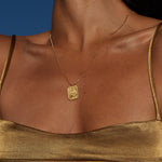 Gold-toned rectangular pendant necklace with Ganesha deity relief, worn on thin chain at chest level.