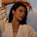 A woman wearing Full Bloom Lotus Petal Earrings, embodying spiritual jewelry and meditation vibes. The earrings symbolize new beginnings and personal transformation, complementing her elegant style. Captured in a serene setting, the photo reflects a meaningful connection to spirituality, manifestation, and protection, perfect for yoga practitioners and those embracing their zodiac journey.