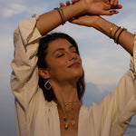 A serene woman wearing the Inner Knowing Labradorite Snake Necklace, symbolizing intuition and transformation, surrounded by other spiritual jewelry perfect for meditation and manifestation, evoking meanings of protection and connection to the sun and moon.