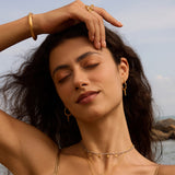 Beautiful woman in nature wearing Drops of Beauty Dot Hoop Earrings, encapsulating the essence of spiritual jewelry, protection, and meaningful expression through style.