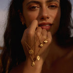 A close-up of a woman wearing the Shifting Consciousness Snake Necklace, showcasing the delicate design of spiritual jewelry that symbolizes transformation and renewal. This beautiful talisman is perfect for meditation and expresses meaningful connections with the sun, moon, and zodiac, enhancing your yoga practice and manifestation journey.