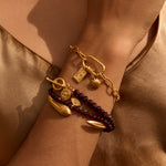 The Balanced Beginnings Garnet Lotus Bracelet displayed elegantly on a wrist, showcasing its garnet gemstones and 18kt gold plate lotus pendant. This spiritual jewelry piece is perfect for meditation and serves as a powerful talisman for meaningful manifestation and protection, bringing the energy of the sun and moon into your yoga practice.
