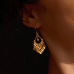 An elegant model wearing Beauty Unveiled Chandelier Earrings, featuring a stunning gold design that catches the light. These earrings symbolize new beginnings and offer protection, ideal for those who practice yoga and seek meaningful spiritual connections.