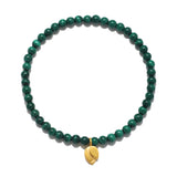 A circular stretch bracelet made of small round green banded malachite beads with a small gold lotus bud charm hanging at the bottom.