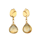 A pair of gold earrings with matte lotus-shaped tops and faceted pale yellow teardrop gemstones hanging from wire-wrapped loops.