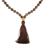 A necklace of faceted smoky brown beads, knotted with brown thread, ends in a gold-toned bead and a long brown tassel.