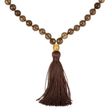 A necklace of faceted smoky brown beads, knotted with brown thread, ends in a gold-toned bead and a long brown tassel.