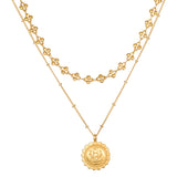 Two-layer gold-toned necklace set with decorative geometric charms on upper chain and circular medallion pendant on lower cha