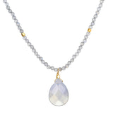 A necklace of small gray faceted beads with two gold accent beads holds a pale, milky teardrop-shaped pendant.