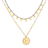 Two-layered gold-tone necklace set with gray beads, small gold charms, and engraved circular pendant.