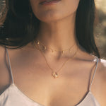 Two-piece gold necklace set with sun pendant and moon-and-star charm chain worn on model.