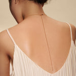 Back view of a woman wearing the Story of Pisces Zodiac Necklace, showcasing the elegant 18kt gold-plated design that embodies spiritual jewelry, perfect for meditation and as a talisman. This zodiac-inspired piece not only symbolizes uniqueness but also enhances meaningful connections through its protective charm, ideal for sun and moon energies, yoga practices, and manifestation journeys.
