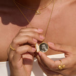 Gold-toned butterfly pearl locket necklace with oval pendant containing a sepia photograph, worn on gold chain.