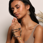 A serene model with closed eyes clasping the Beacon of Creativity Fancy Jasper Celestial Mala in hands, symbolizing yoga, spirituality, and the essence of meaningful talismans in meditation.