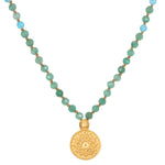 Mala necklace with green faceted beads, light blue accent beads, gold spacers, and gold circular pendant with geometric star 