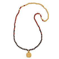 Beaded mala necklace with black, red, and golden-yellow stones, featuring a gold-toned circular pendant at the base.