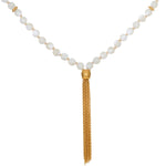 Beaded mala necklace with white mother of pearl spheres separated by gold spacers and gold tassel pendant.