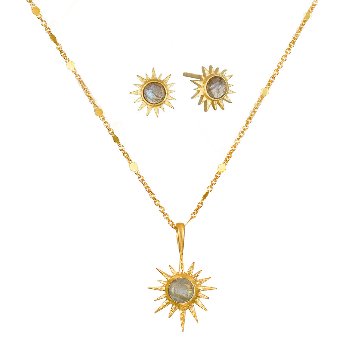 A gold chain necklace with a sunburst pendant and matching stud earrings, each set with a round gray labradorite stone.