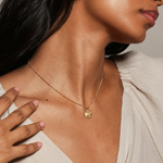 A profile view of a woman adorned with the Vibrant Self Multi Stone Lotus Necklace, highlighting its radiant design as a talisman for yoga and spiritual practice, symbolizing new beginnings and the sun's energy.