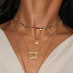 The Sacred Commencement Lotus Necklace displayed layered with other spiritual jewelry, featuring colorful beads and gold accents, perfect for meditation and manifestation, emphasizing new beginnings and protection in yoga practices.