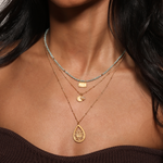 Layered necklaces featuring the Dawn of Renewal Lotus Necklace among other pieces, embodying a spiritual style for yoga and protection, ideal for those seeking a meaningful talisman.