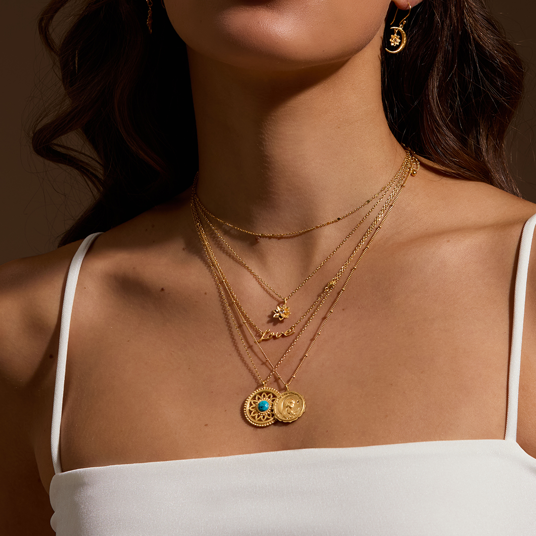 A close-up of the Nurture Intuition Turquoise Mandala Necklace layered with other gold necklaces, showcasing the charm and beauty of spiritual jewelry designed for yoga, protection, and personal expression.