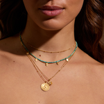 Close-up of a model showcasing the Soul Renew Gold Lotus Necklace along with other delicately layered necklaces. This spiritual jewelry shines with the symbolism of the lotus flower, representing meaningful connections to sun, moon, and the universe's energies in yoga and meditation.