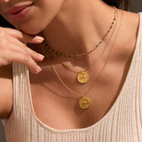 Close-up of the Cradled in Positivity Hamsa Necklace layered with other gold pieces. This spiritual jewelry emphasizes protection and meaningful connection to celestial energies, ideal for the zodiac and meditation.