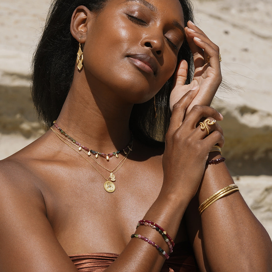 A serene image featuring the Cradled in Positivity Hamsa Necklace being worn with bracelets and earrings. This ensemble of spiritual jewelry embodies the essence of manifestation, yoga, and meaningful protection.