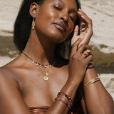 A serene image featuring the Cradled in Positivity Hamsa Necklace being worn with bracelets and earrings. This ensemble of spiritual jewelry embodies the essence of manifestation, yoga, and meaningful protection.