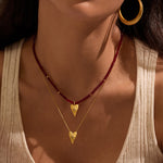 A woman wearing the Healing Heart Red Onyx Heart Necklace layered with a golden heart pendant, showcasing its spiritual jewelry features for meditation and protection. The necklace highlights the meanings of love and healing, perfect for yoga and meditation practices.