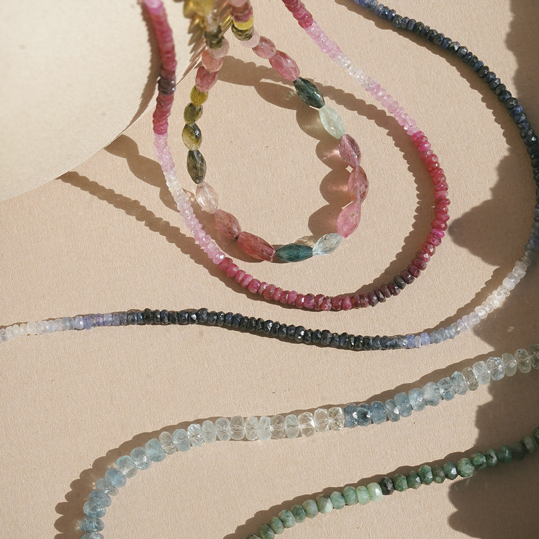Five strands of colorful gemstones including ruby in different shades, highlighting the Shades of Passion 14kt Gold Ruby Necklace as a talisman for spiritual and protective energy during meditation and yoga.