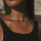 A model wearing the Shades of Love 14kt Gold Sapphire Necklace, highlighting the beautiful shades of sapphire against the skin. This necklace represents spiritual and meaningful adornment, ideal for those who seek protection and harmony in their daily lives, connecting with the energies of the sun and moon.