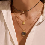 Stylish layered necklaces including the Dreams of Prosperity Pyrite Necklace, showcasing elegance through spirituality. The combination of various necklaces highlights the essence of spiritual adornment, captivating both yoga practitioners and those seeking meaningful talismans for protection and manifestation. Emphasizing the sun and moon theme, this look is ideal for meditation and zodiac lovers.
