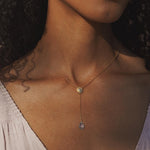 A model wearing the Speak with Strength Chakra Lariat Necklace with a soothing expression, showcasing the beautiful blue topaz drop as a talisman for positive energy, perfect for spiritual and yoga practices.