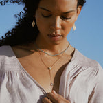 A woman modeling the Speak with Strength Chakra Lariat Necklace along with other jewelry, radiating confidence and wisdom, embodying the essence of spiritual protection and meaningful connections.